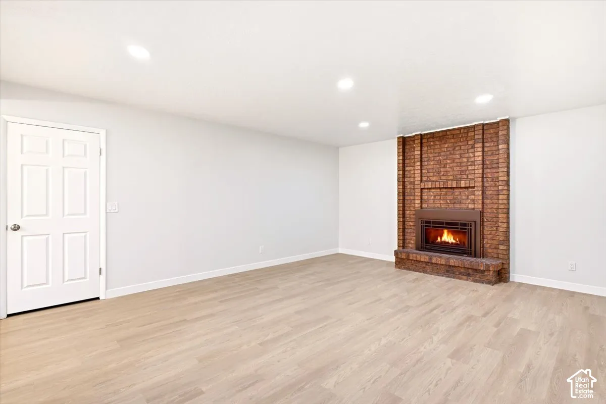 Interior space featuring wood-finish flooring, recessed lighting, and a floor-to-ceiling brick fireplace with a raised hearth