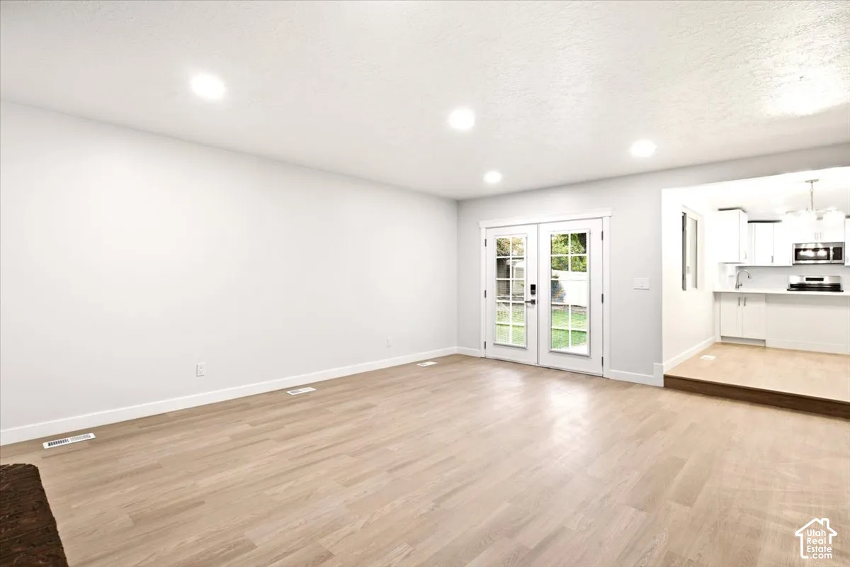 Open-concept interior featuring wood-finish flooring, recessed lighting, and double glass-paned doors