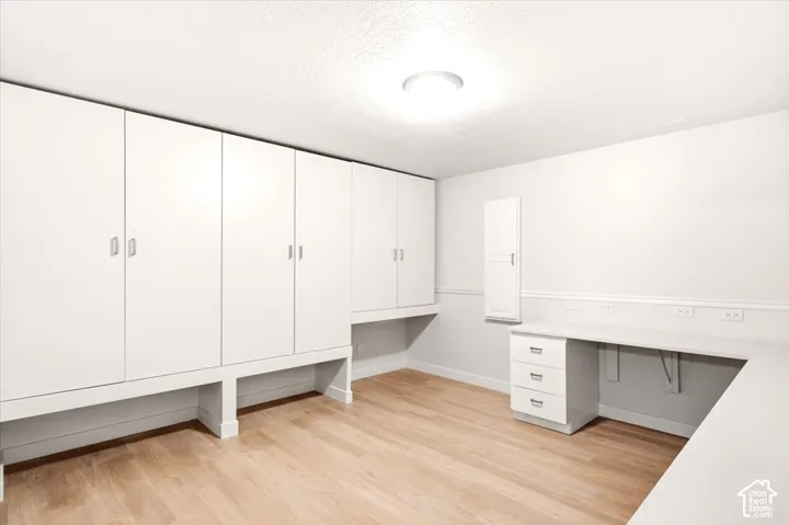 Built-in floor-to-ceiling cabinetry, integrated desk with drawer storage, and light wood-finish flooring