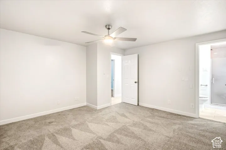 Neutral-toned wall-to-wall carpeting, brushed-nickel ceiling fan with integrated lighting, and white six-panel interior doors