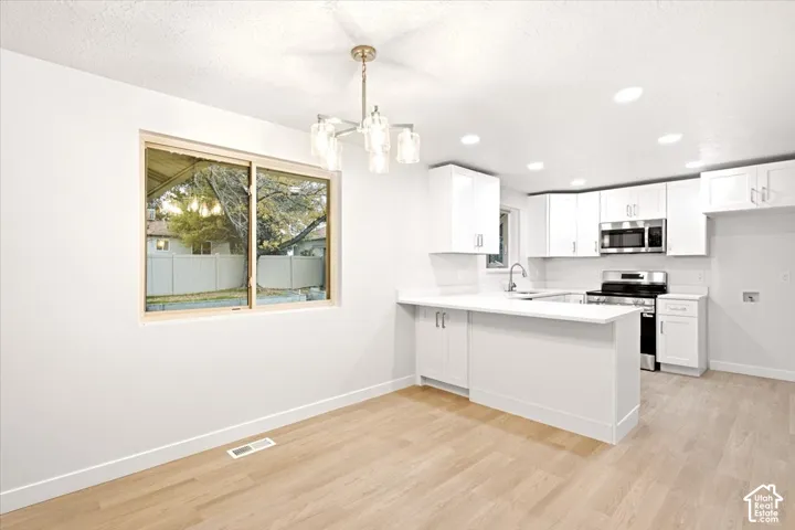 Kitchen featuring white cabinetry, solid-surface countertops, stainless steel appliances, recessed lighting, and wood-finish flooring