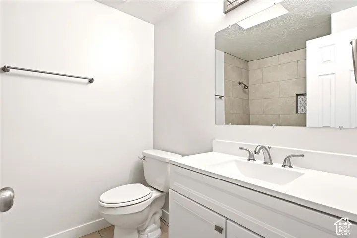 Bathroom featuring a white vanity cabinet with an integrated sink, polished metal widespread faucet, expansive wall-mounted mirror, and tile-surround shower area