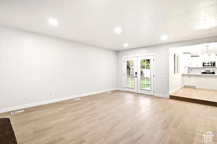 Open-concept interior featuring wood-finish flooring, recessed lighting, and double glass-paned doors