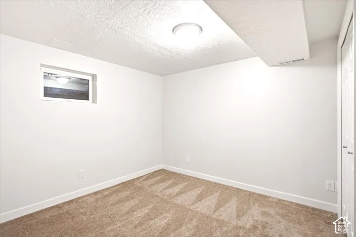 Neutral-toned carpeting, crisp white walls, recessed ceiling lighting, single-pane casement window, and a white paneled closet door