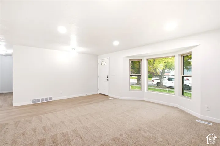 Interior space featuring recessed lighting, wall-to-wall carpeting, wood-finish flooring, and a multi-pane bay window