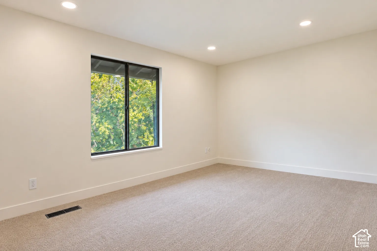 Neutral-toned carpeted flooring, recessed lighting, and a single-pane window featuring a black frame