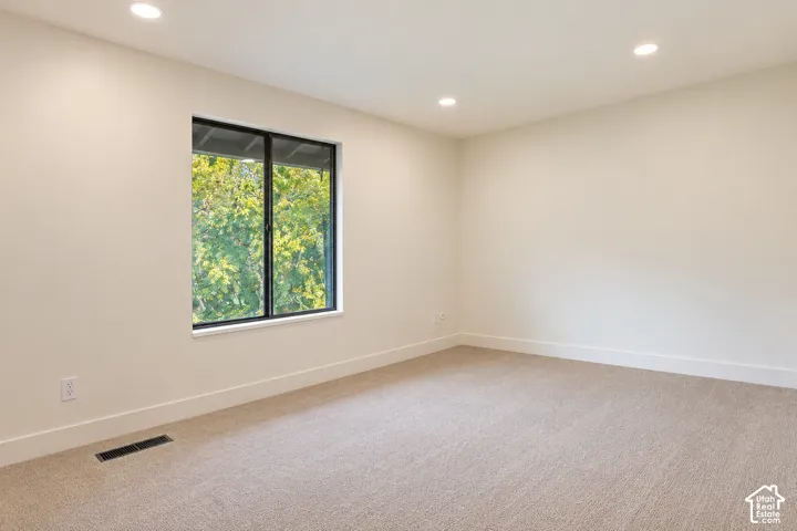Neutral-toned carpeted flooring, recessed lighting, and a single-pane window featuring a black frame