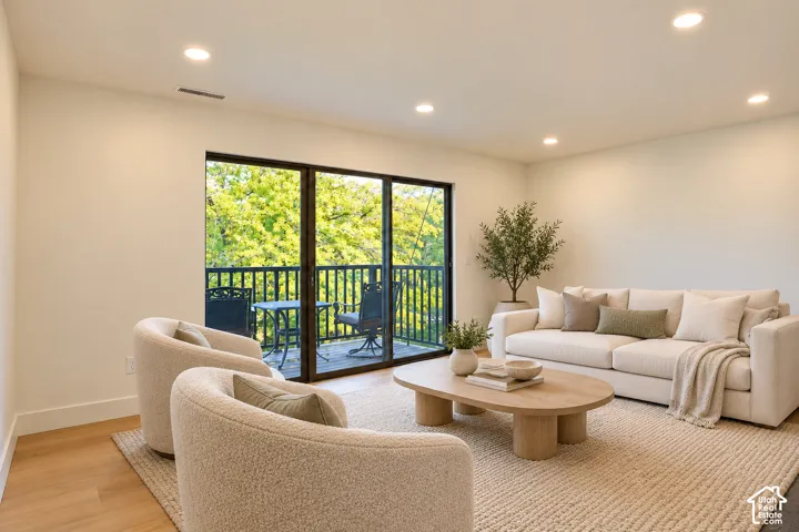 Interior space featuring wood-finish flooring, recessed lighting, and large sliding glass doors opening to an exterior balcony with railing Virtually Staged