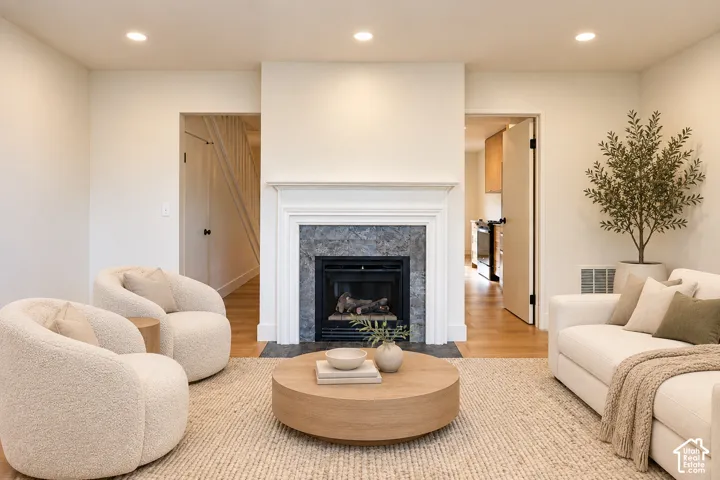 Fireplace featuring a stone-tiled surround, a crisp white mantel, recessed lighting, and wood-finish flooring Virtually Staged