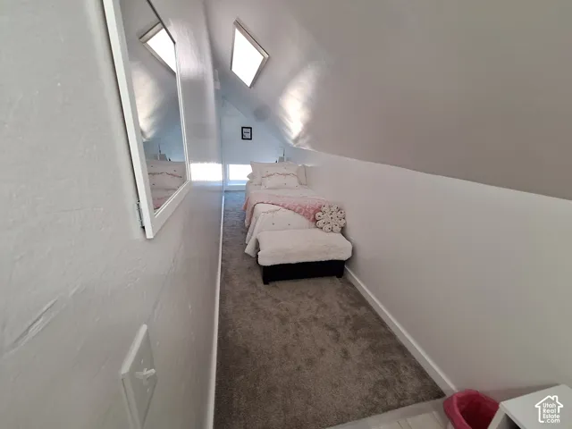 Attic room featuring a sloped ceiling, skylights, and wall-to-wall carpeting