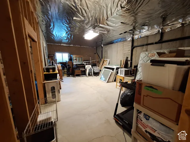 Unfinished basement space featuring exposed wood framing, concrete flooring, concrete foundation walls, and reflective insulation on the ceiling
