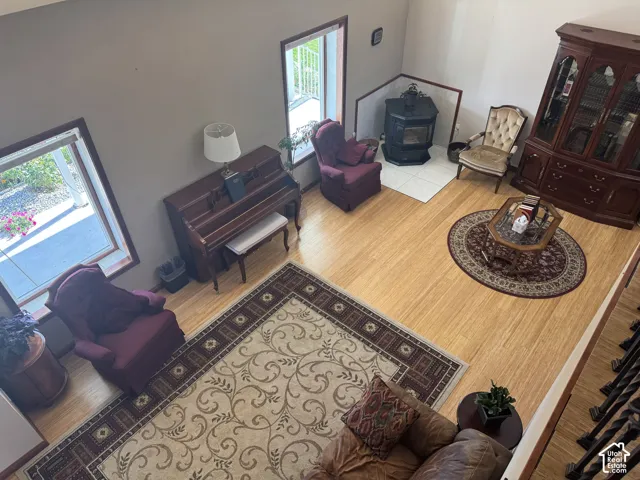 High-ceiling living area featuring wood-finish flooring, a corner pellet stove with a tiled hearth, and oversized windows