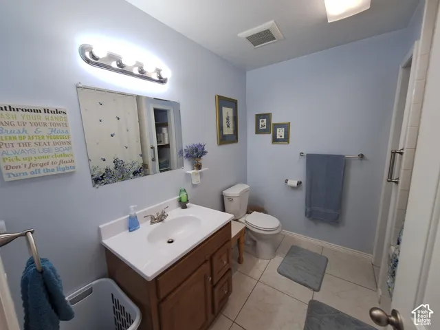 Upstairs bathroom featuring a vanity with a white countertop and integrated sink, ceramic tile flooring, chrome bathroom hardware, wall-mounted light fixture, and a framed vanity mirror