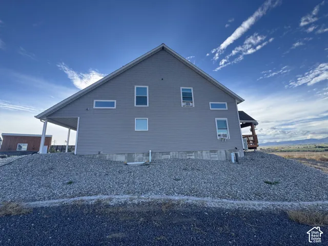 Two-story residence featuring horizontal lap siding, a pitched roofline, exposed concrete foundation, and a covered side porch