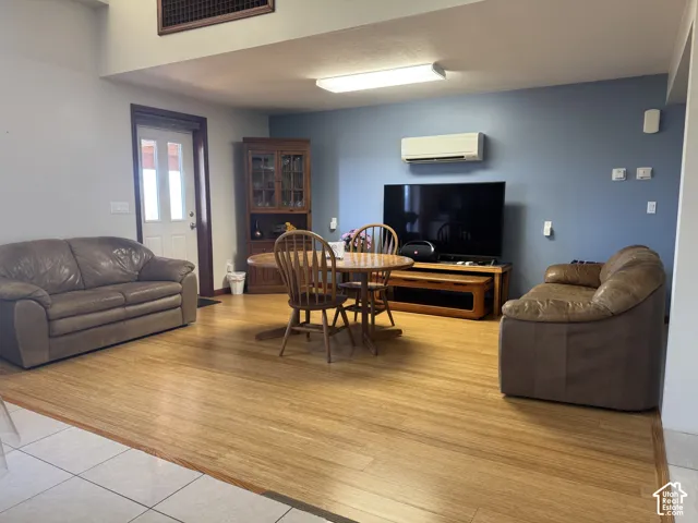 Open-concept area featuring wood-finish flooring, vaulted ceilings, and a wall-mounted ductless mini-split HVAC unit