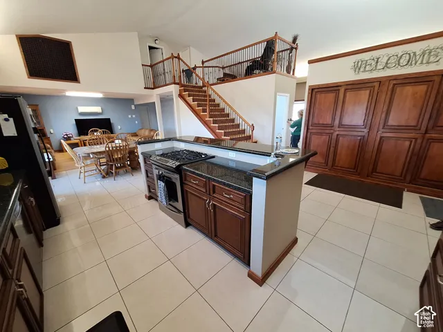Kitchen island featuring granite countertops and integrated gas range, staircase with wood handrails and balusters, and expansive built-in wood cabinetry