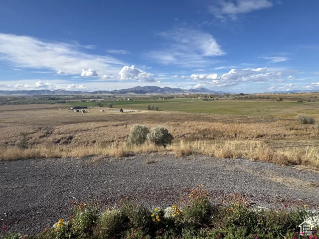 Expansive open acreage featuring native grasses, gravel terrain, and a prominent mountain backdrop