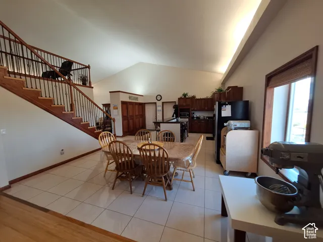Open-concept interior featuring vaulted ceilings, tile flooring, wooden staircase,  and custom wooden cabinetry