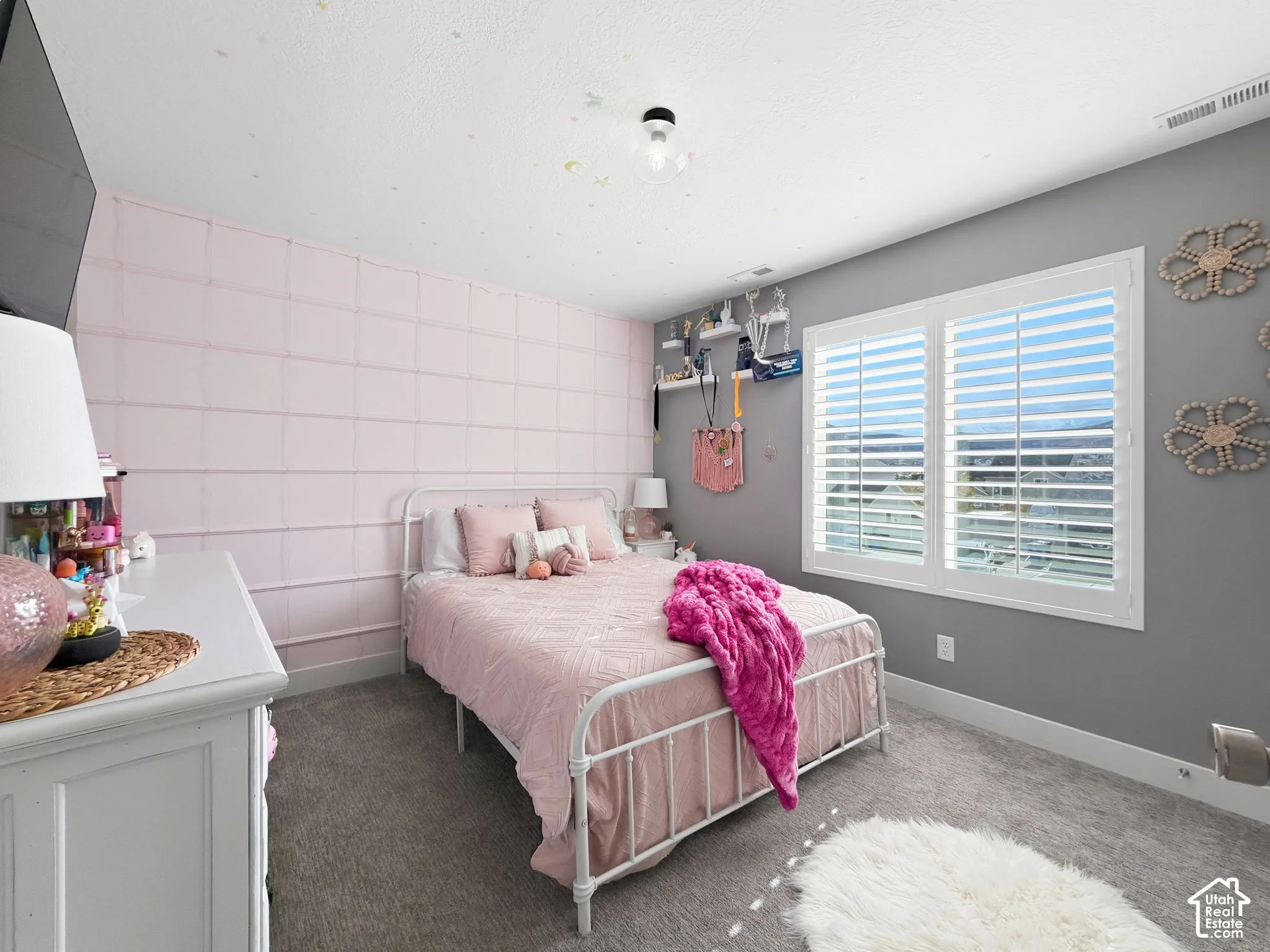 Bedroom featuring wall-to-wall carpeting, a custom-grid accent wall, and interior window shutters