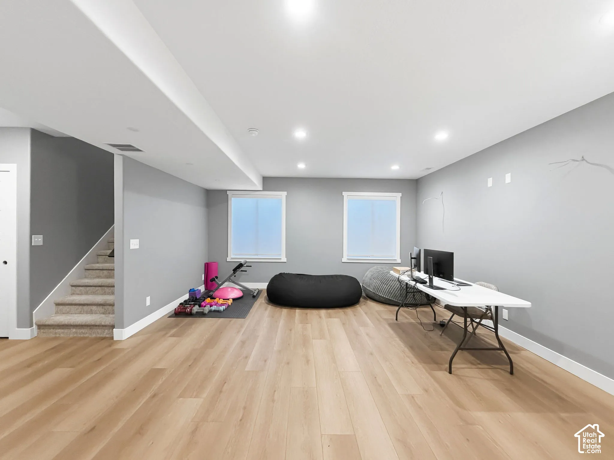 Spacious open-concept interior featuring light wood-finish flooring, recessed lighting, and neutral wall color, complemented by two windows