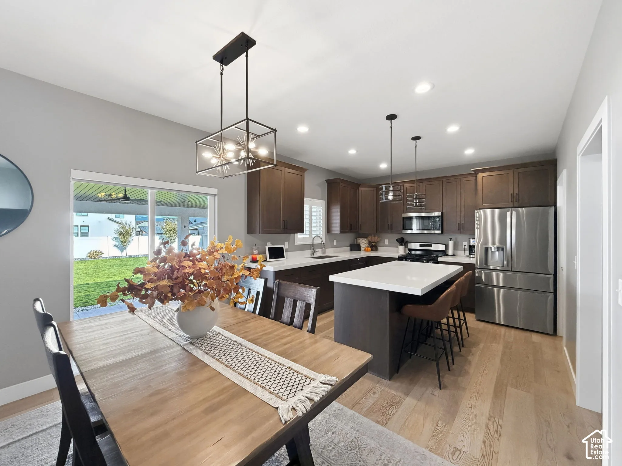 Kitchen featuring wood-finish cabinetry, a central island with a solid-surface countertop, stainless steel appliances, recessed lighting, and wood-finish flooring
