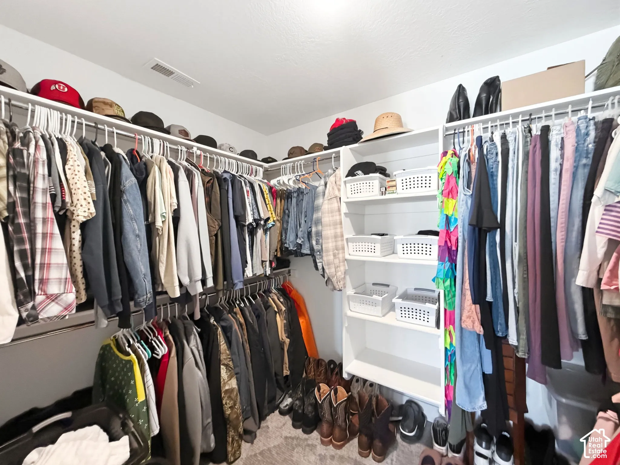 Walk-in closet featuring tiered white wire shelving and built-in vertical cabinetry