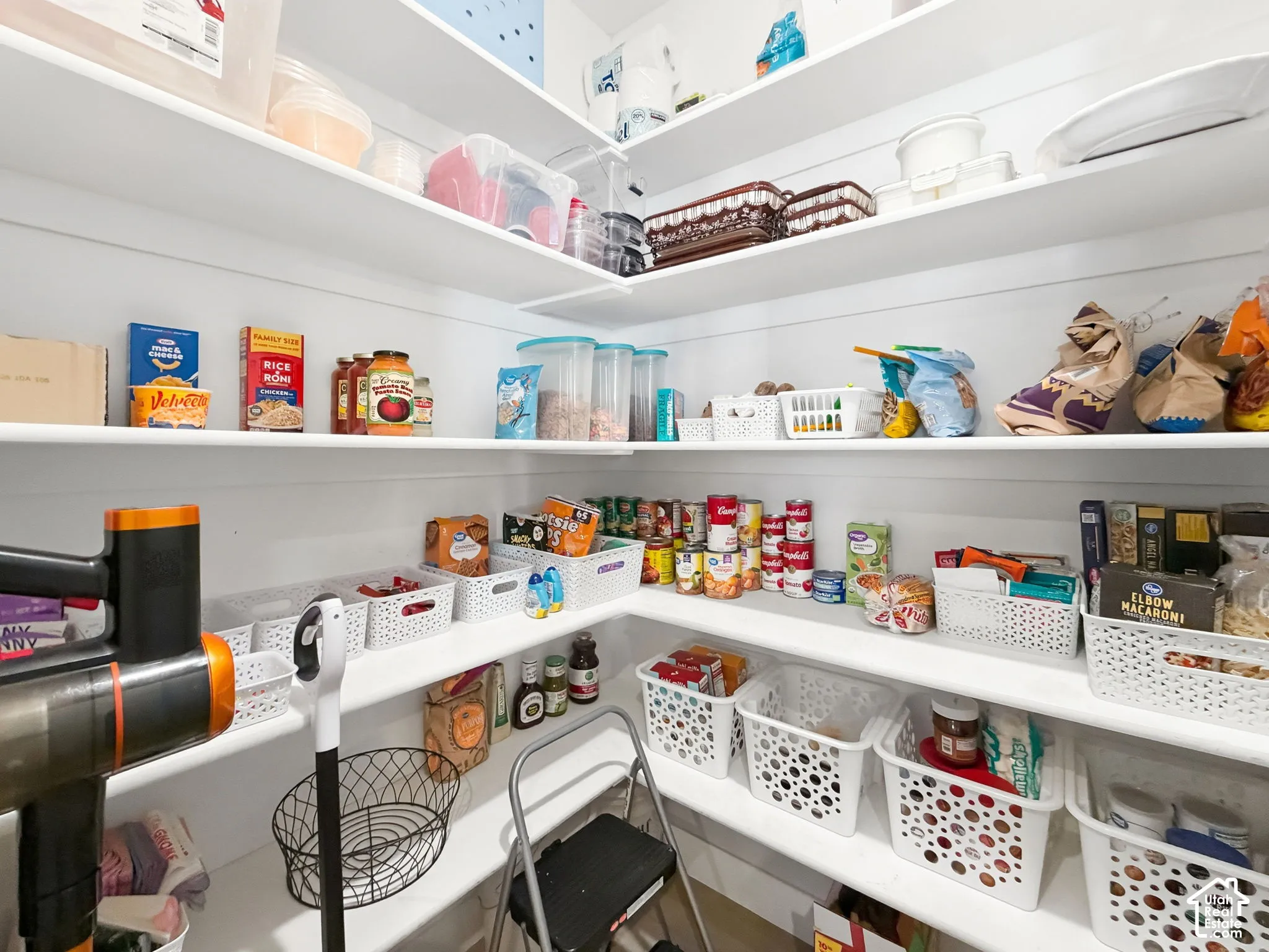 Walk-in pantry featuring white shiplap walls and multi-level wrap-around shelving