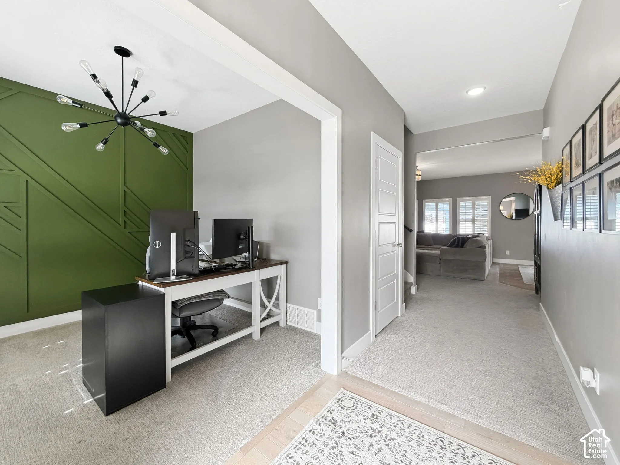 Accent wall featuring geometric millwork, matte black sputnik-style chandelier, and neutral wall-to-wall carpeting