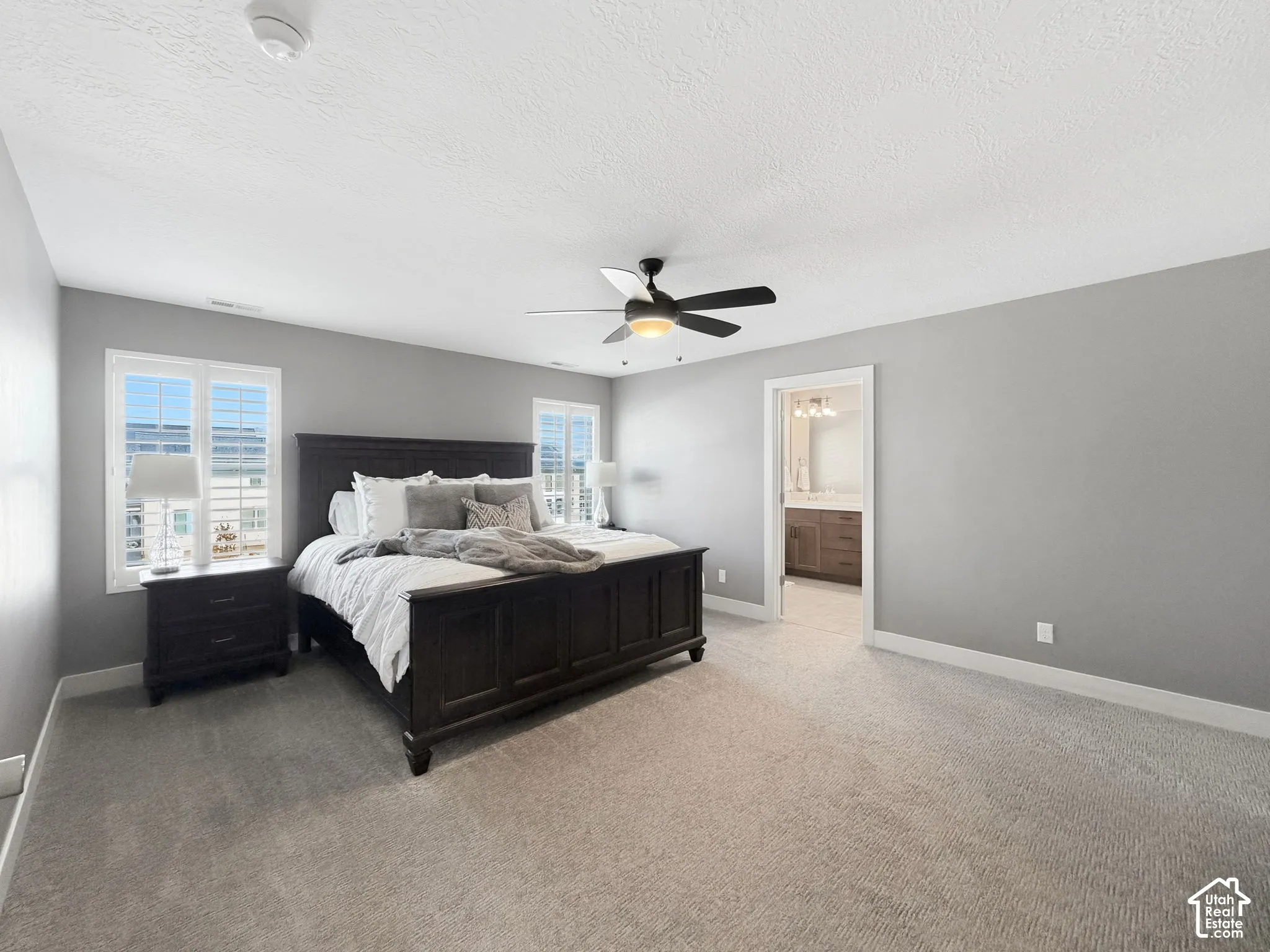 Neutral interior walls, wall-to-wall carpeting, ceiling fan with integrated lighting, and dual windows