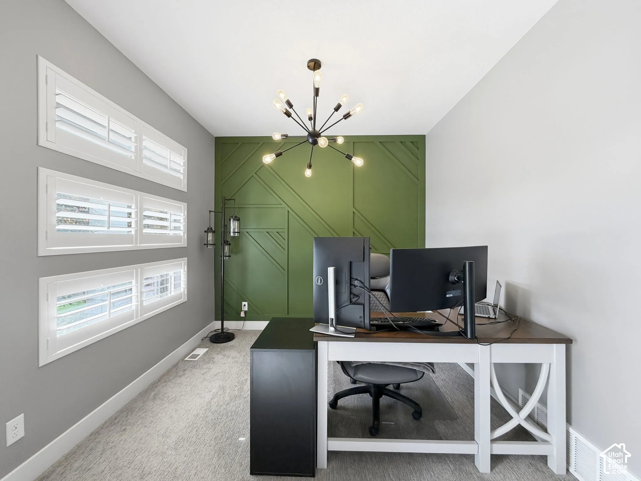 Accent wall with geometric millwork, matte black sputnik-style chandelier, and triple-stacked windows with white plantation shutters
