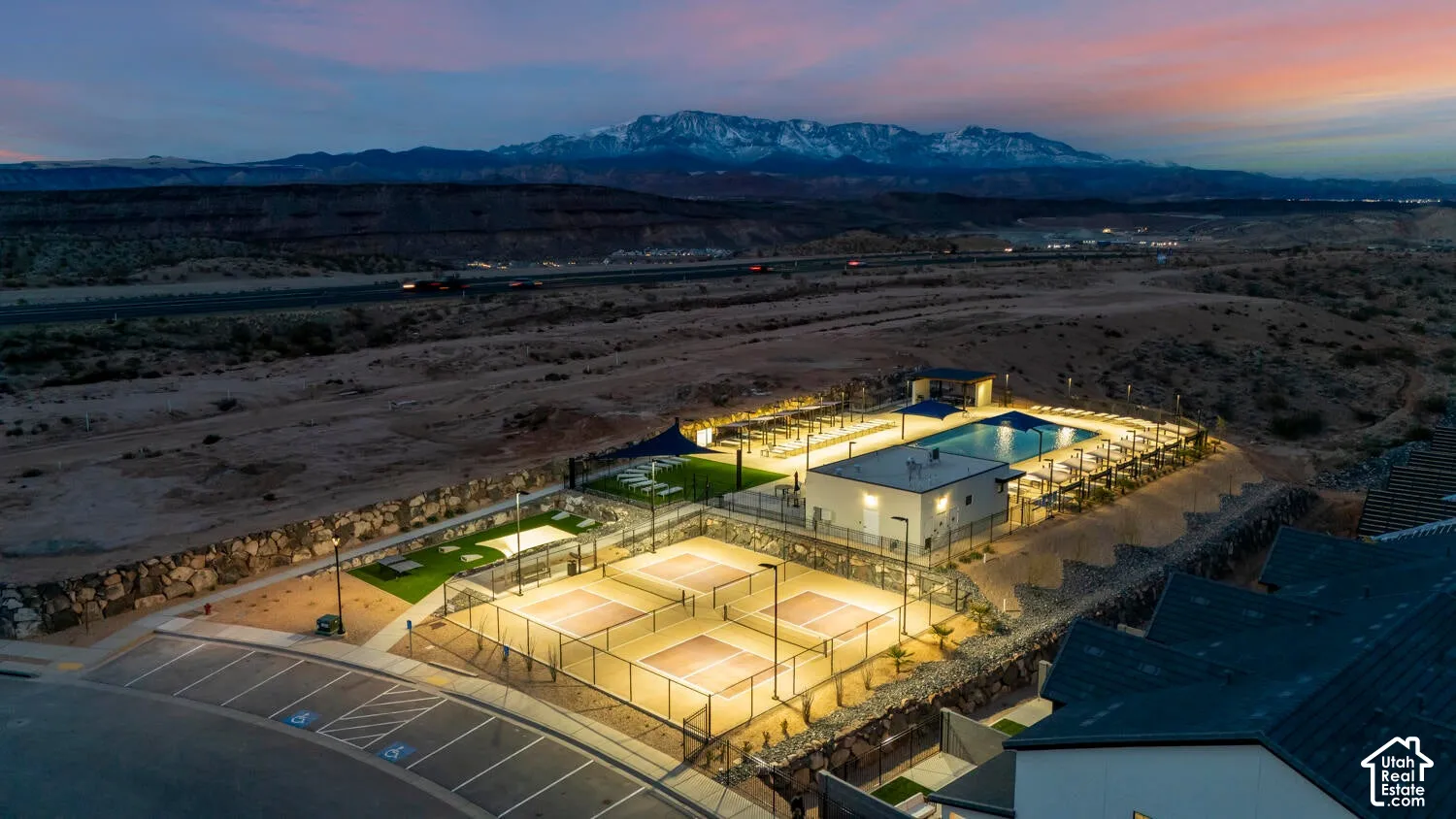 Outdoor recreation area featuring a swimming pool, multiple pickleball courts, synthetic turf zones, and mountain backdrop