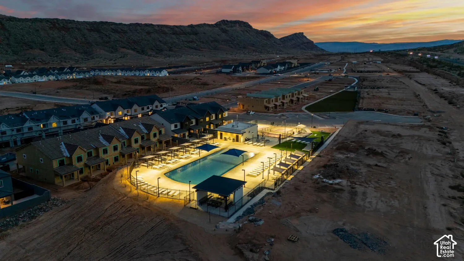 Community swimming pool featuring a concrete deck, shade structures, and mountain backdrop