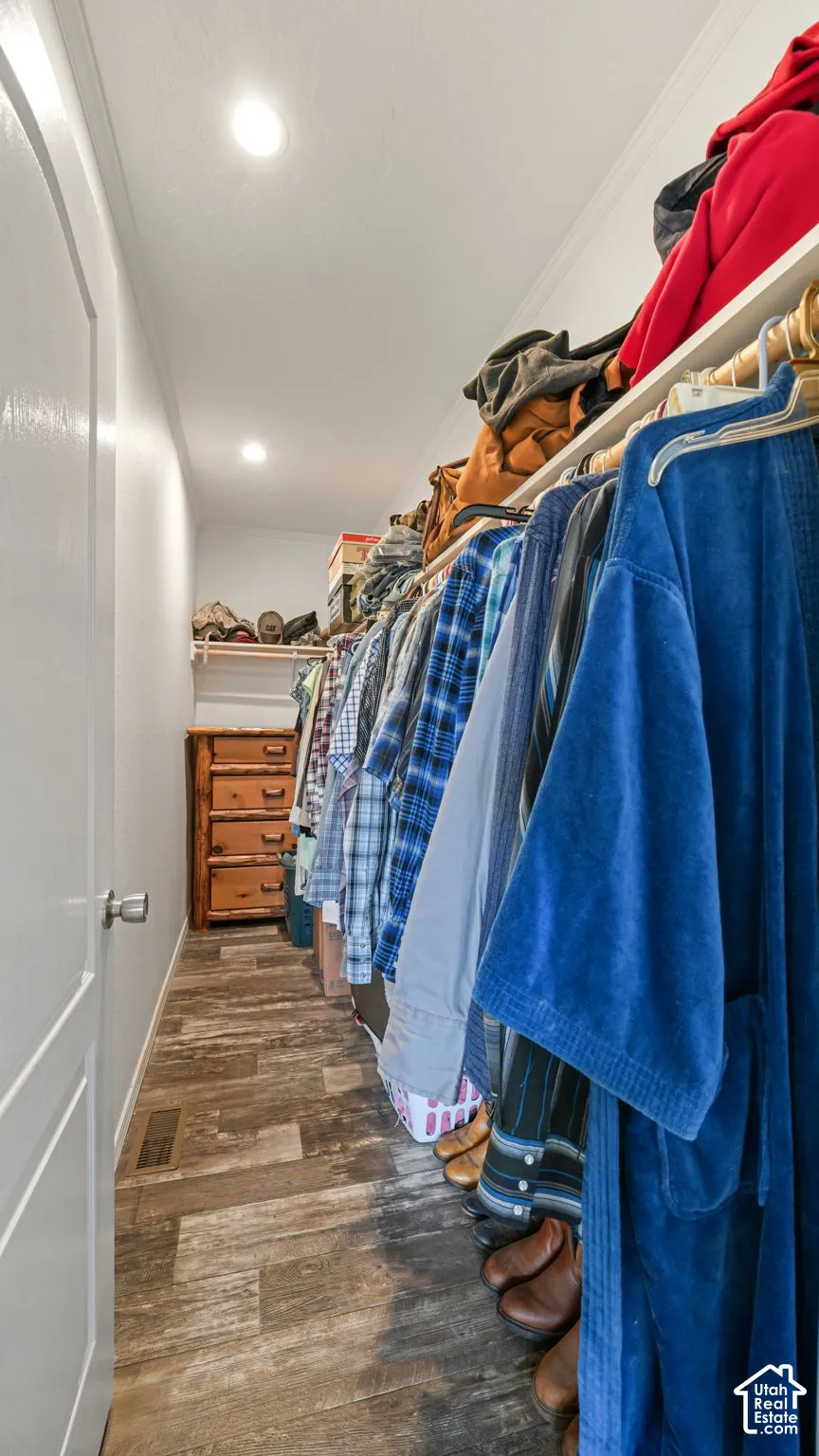 Walk-in closet featuring wood-finish flooring, recessed lighting, and tiered built-in shelving