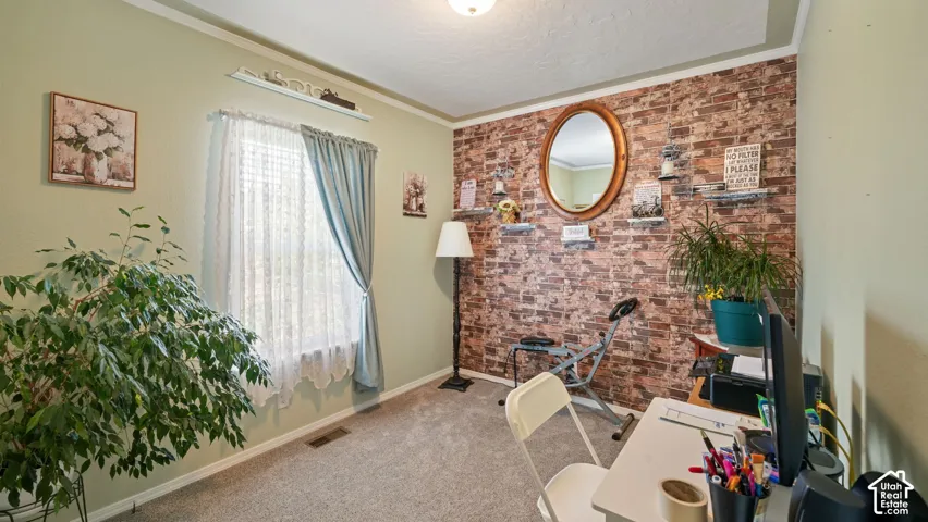 Interior room featuring a textured brick-style accent wall and neutral carpeting