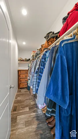 Walk-in closet featuring wood-finish flooring, recessed lighting, and tiered built-in shelving