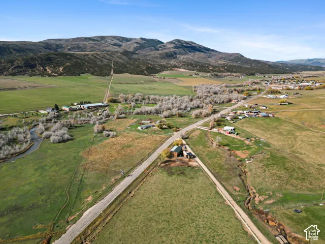 Aerial perspective of expansive acreage featuring mountain terrain, open pastureland, and established trees