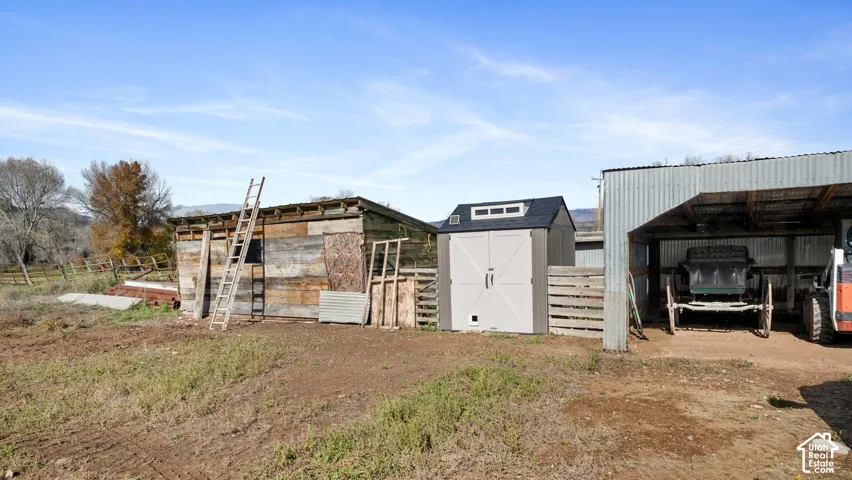 Exterior structures featuring a covered metal-roofed bay, a separate storage building with double-door entry, and wood-paneled siding