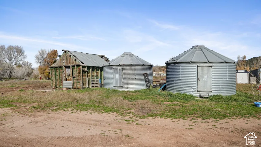 Two cylindrical metal storage structures and a timber-framed wood structure with a metal roof