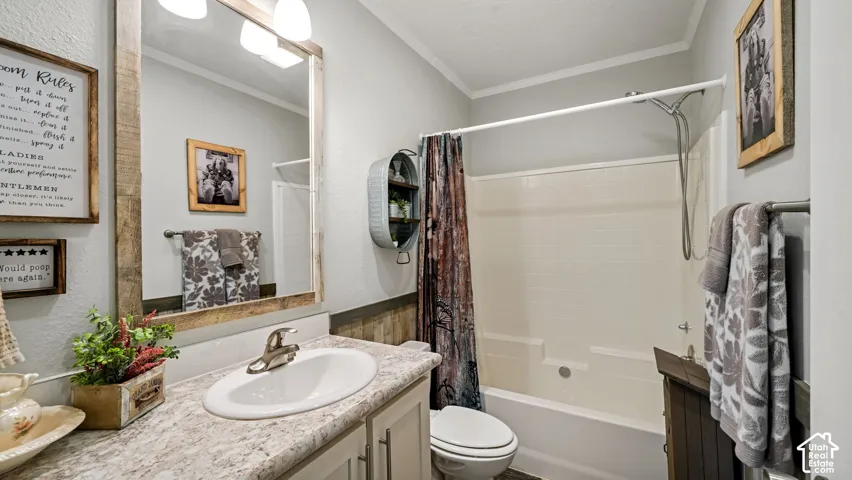 Bathroom featuring a wood-framed mirror, vanity with a stone-finish countertop and integrated sink, molded tub and shower surround, and rustic wood paneling