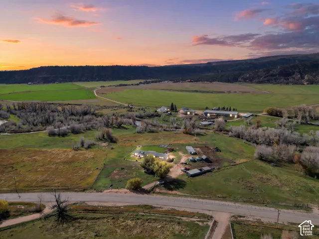 Aerial landscape featuring expansive acreage, multiple outbuildings, mature trees, and mountainous terrain
