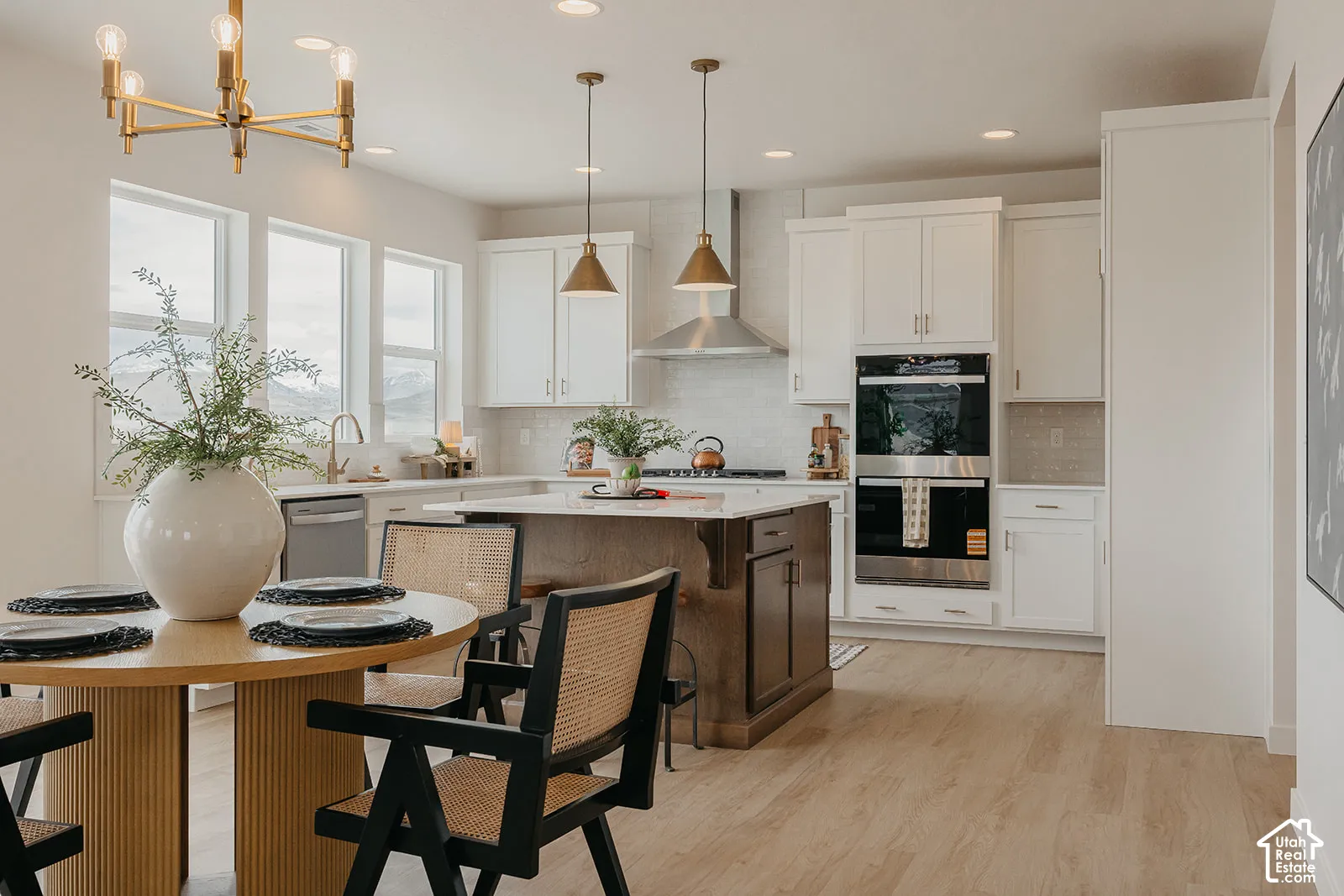 Kitchen featuring white cabinetry, central island with contrasting finish, stainless steel double wall oven, wood-finish flooring, and pendant lighting