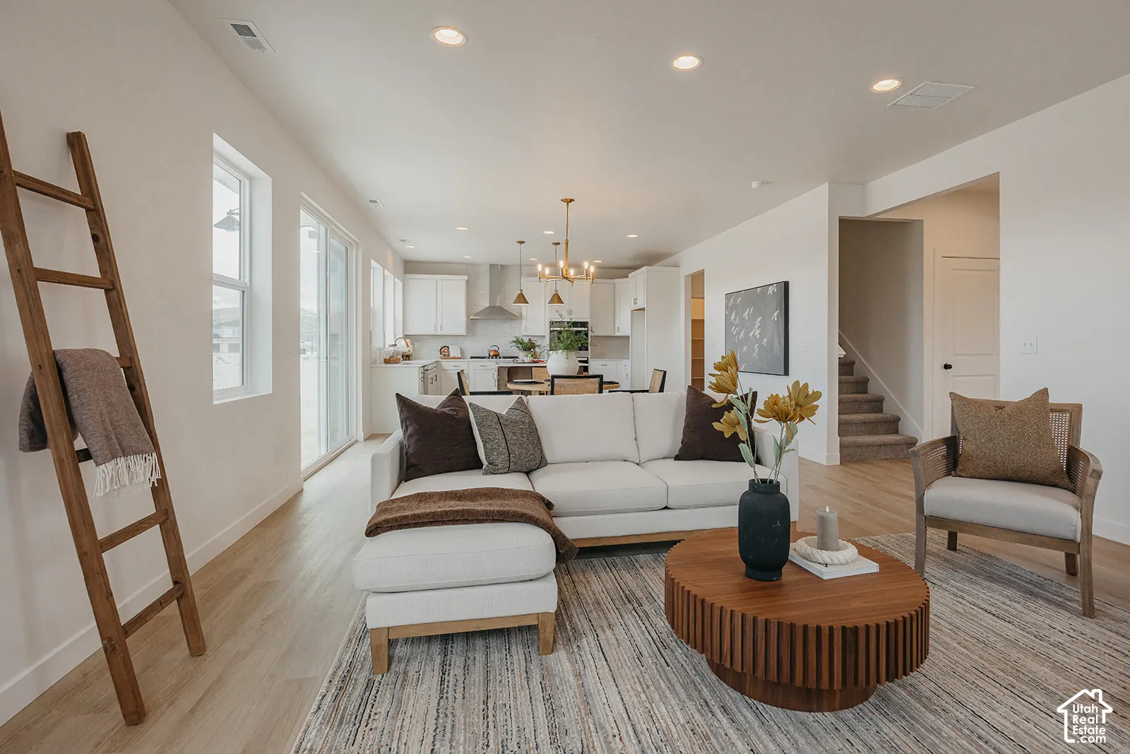 Neutral-toned interior featuring wood-finish flooring, recessed lighting, expansive windows, and a multi-light chandelier fixture