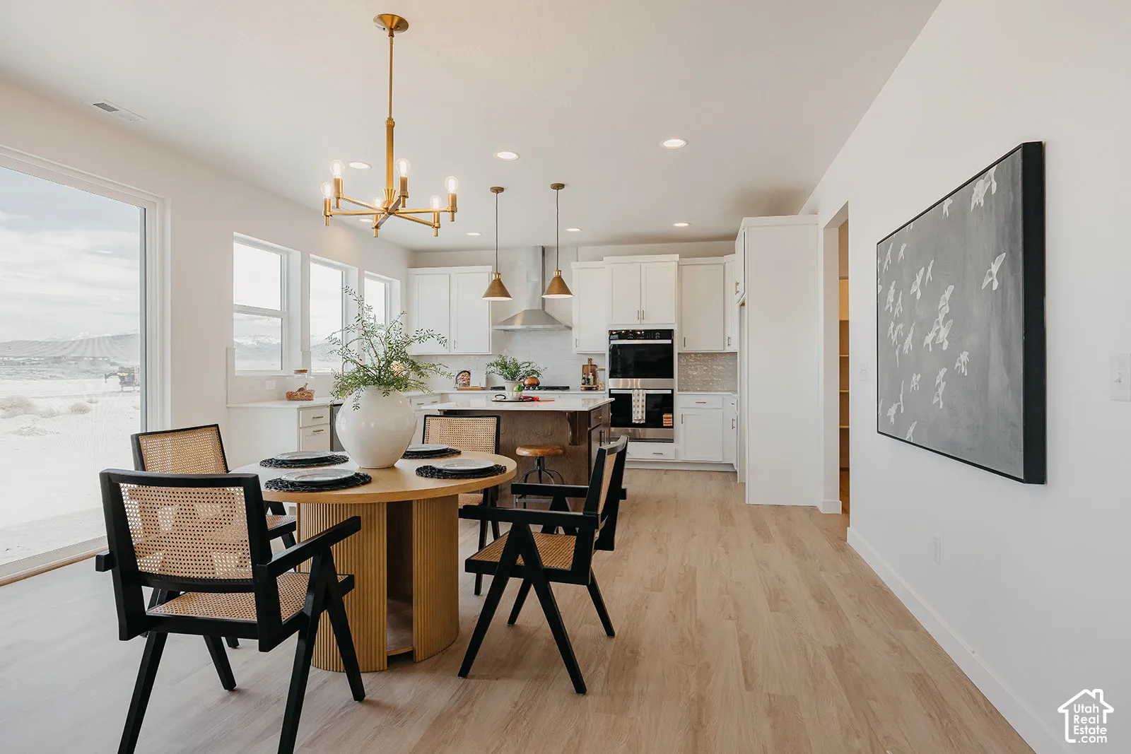 Kitchen and dining area featuring wood-finish flooring, a central island, double wall ovens, recessed lighting, and a multi-arm chandelier