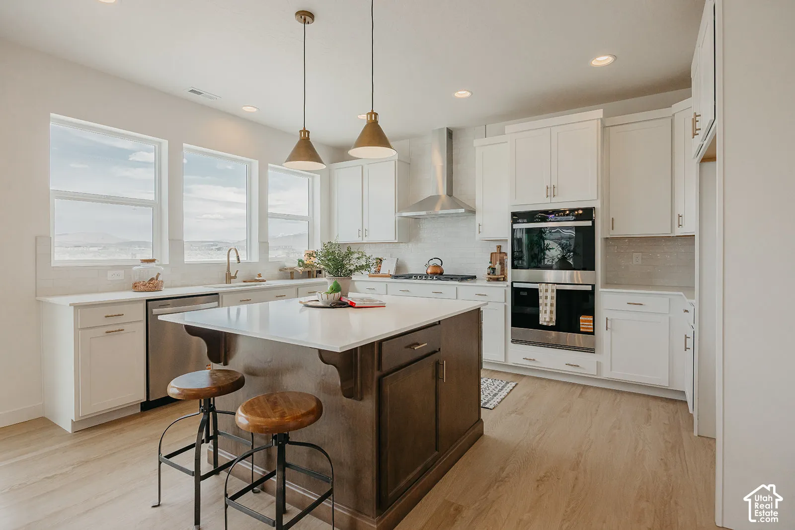 Kitchen featuring white cabinetry, center island with a dark wood finish, stainless steel wall-mounted oven, recessed lighting, and wood-finish flooring
