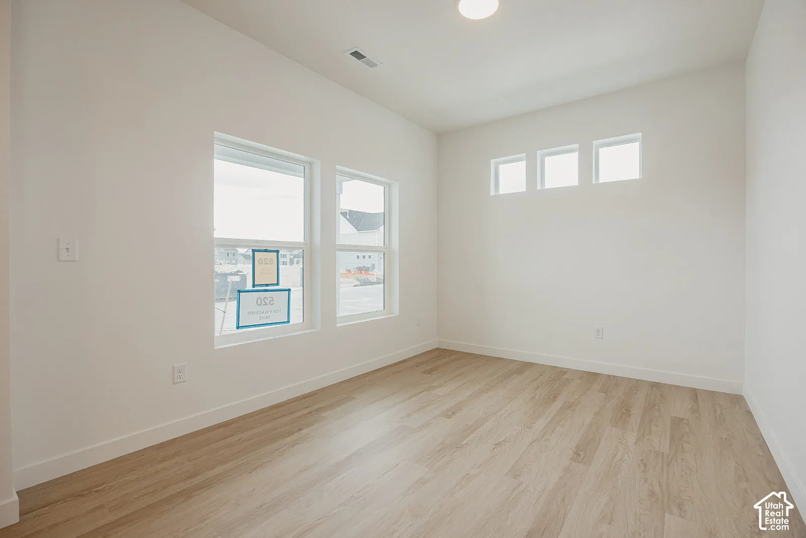 Room featuring high ceilings, wood-finish flooring, and multiple windows including a transom window configuration
