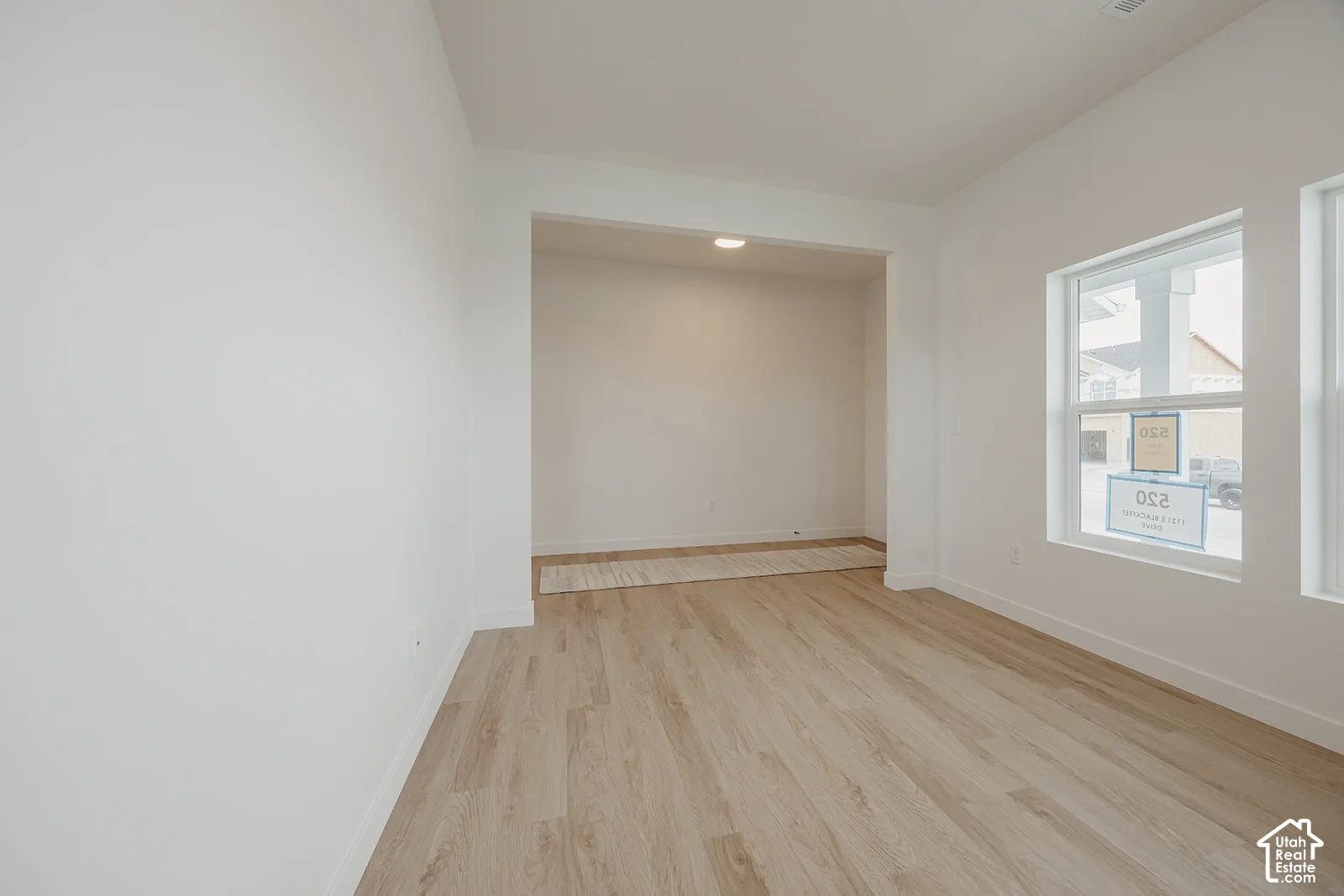 Interior space featuring light-toned wood-finish flooring, neutral walls, recessed ceiling lighting, and windows