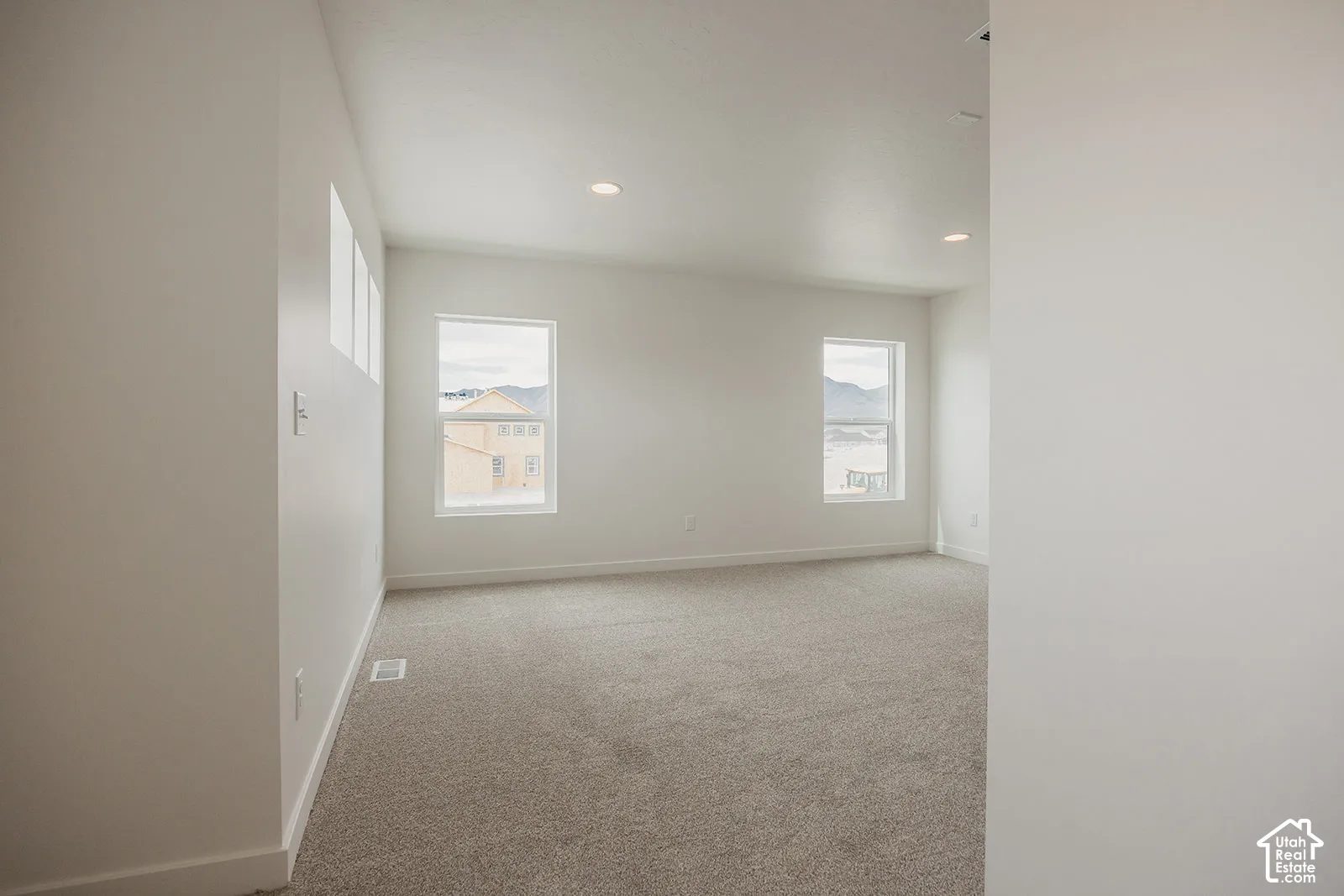 Neutral-toned carpeting, recessed ceiling lighting, and multiple windows