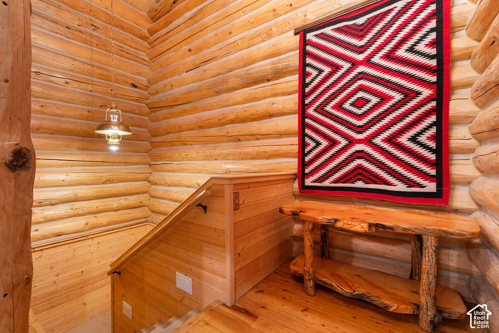 Log walls, natural wood plank flooring, and a metal pendant light fixture