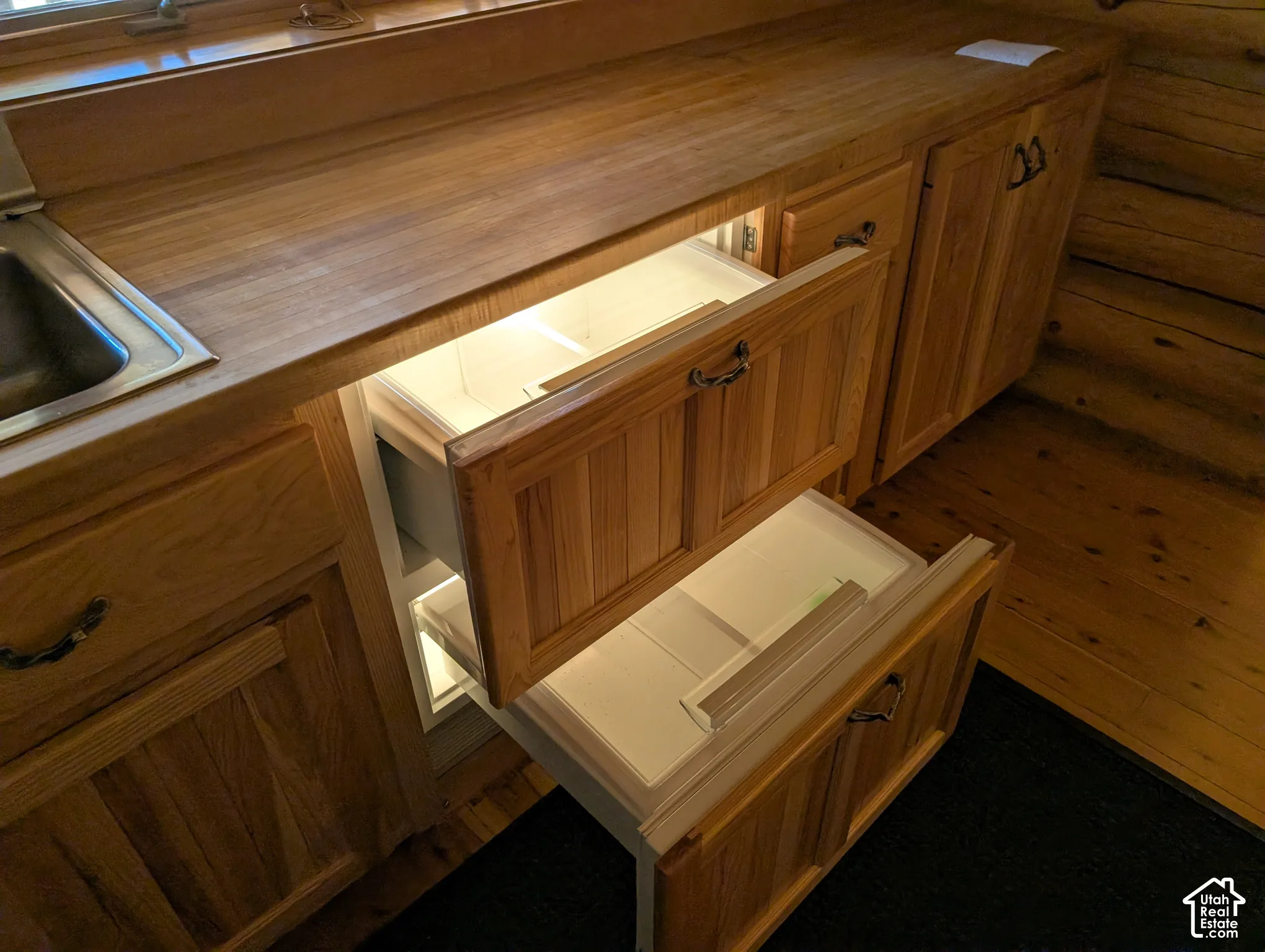 Beautiful wood cabinetry featuring integrated pull-out drawer refrigeration, solid wood countertops, and a stainless steel sink.