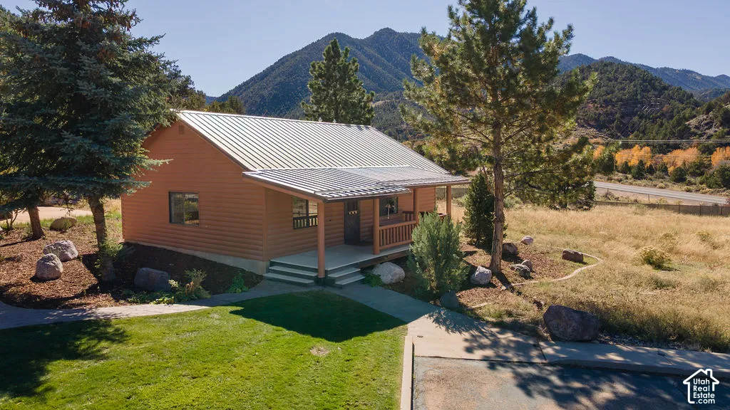 Detached single-story guest home featuring  a covered front porch with a railing, set against a mountainous backdrop